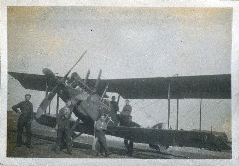 Men posed around a RE8 bi-plane at airfield