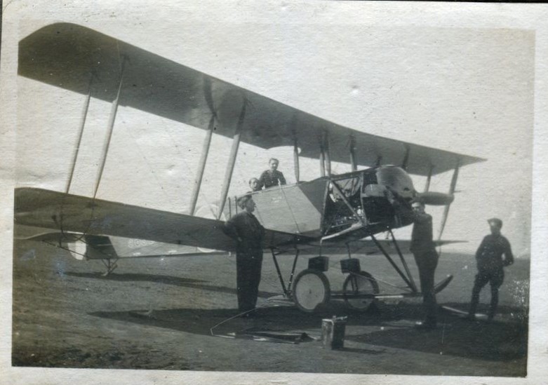 Men posed around an Avro 504 bi-plane at airfield