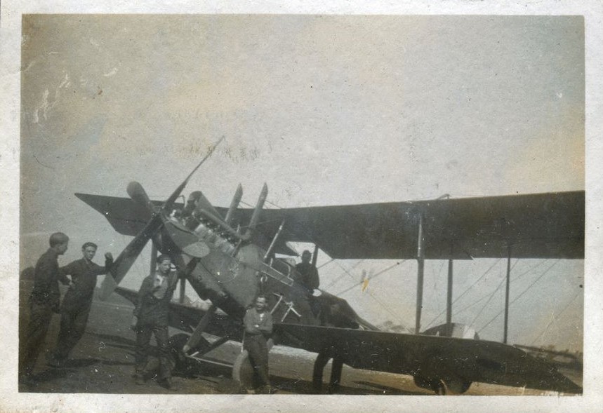 Men posed around a RE8 bi-plane at airfield