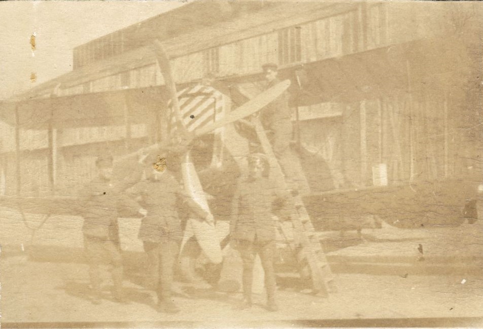 Four men posing round a bi-plane, possibly at RAF Beaulieu
