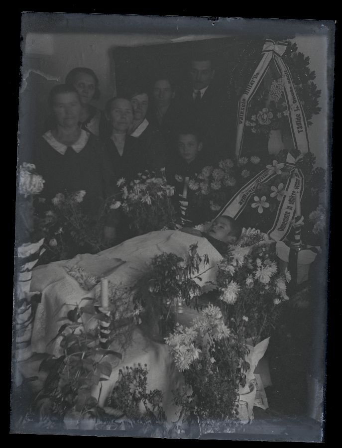 Matusefoto, esiplaanil avatud kirst, kirstu taga seisavad inimesed.