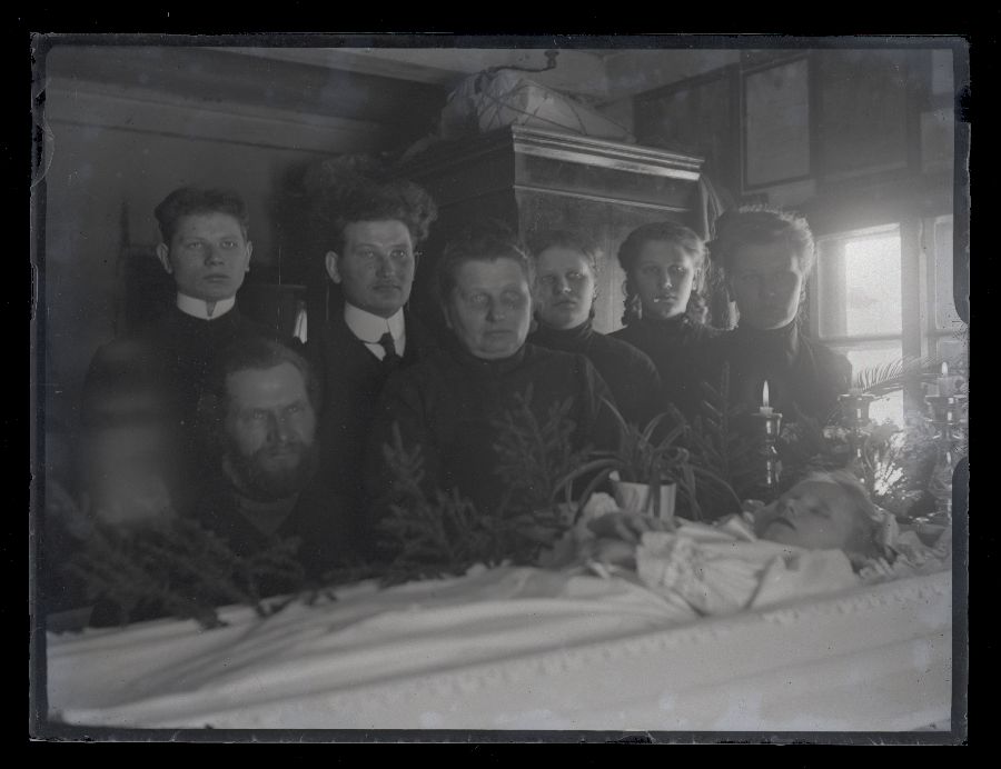 Matusefoto, laps avatud kirstus, kirstu taga seisavad inimesed.
