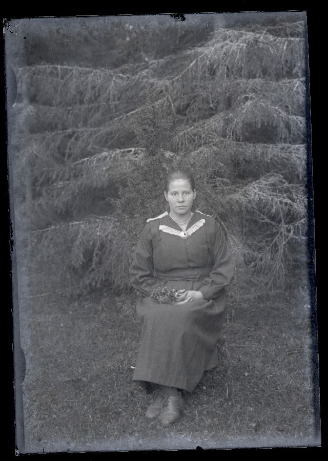 Istuv naine, pildistatud metsas.