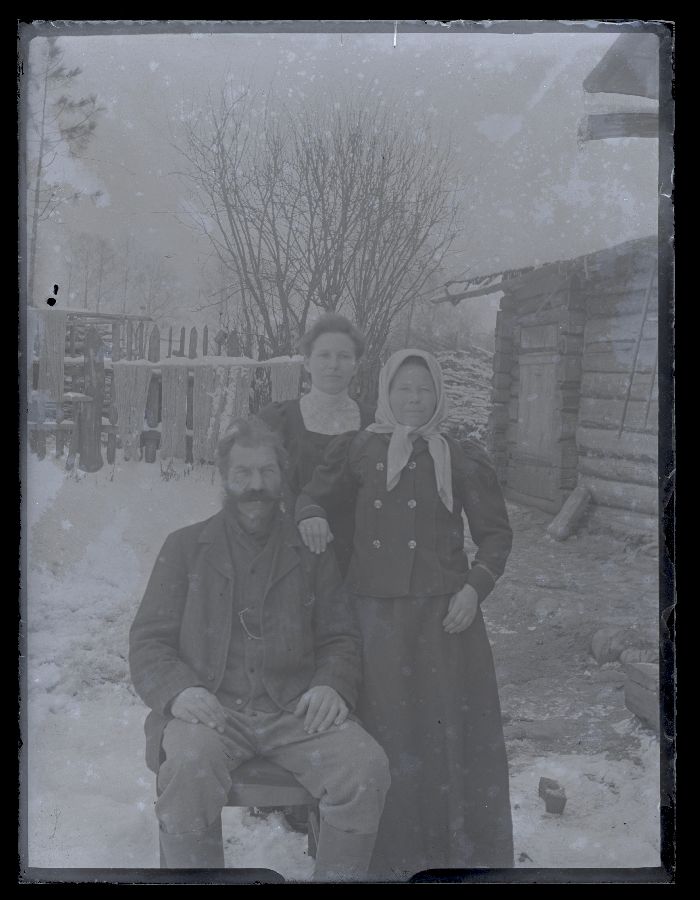 Grupifoto, mees ja kaks naist, pildistatud talvel taluhoovis.