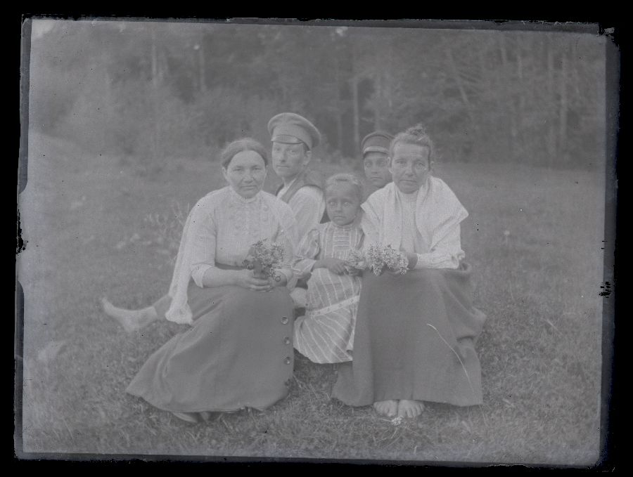 Kaks naist, kaks meest ja väike laps, pildistatud metsa ääres.