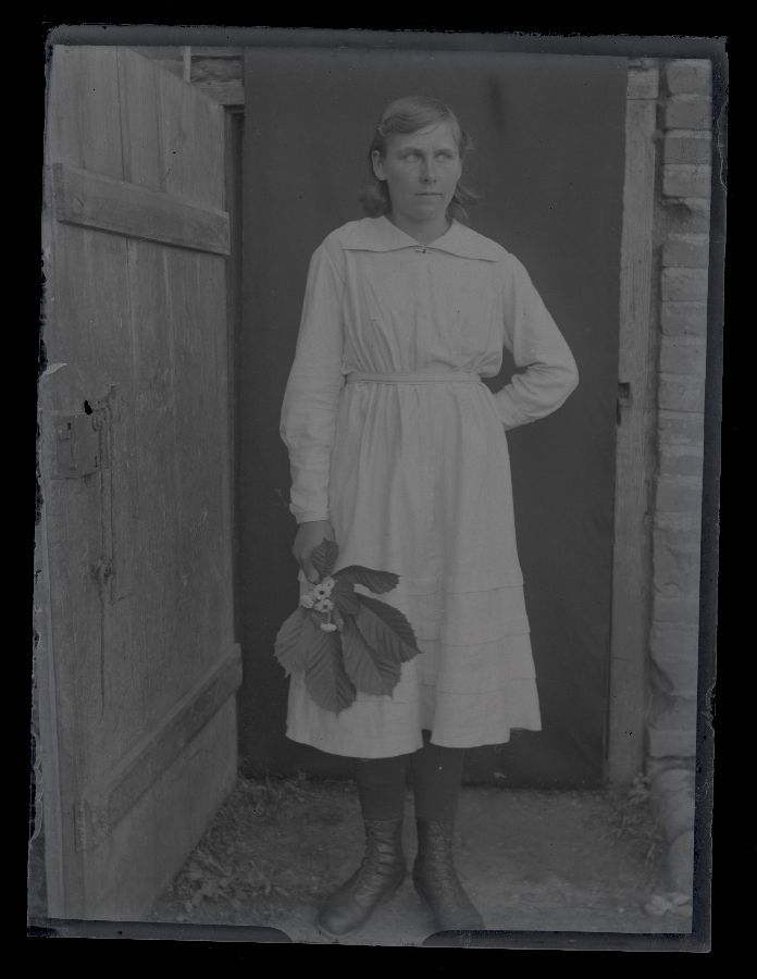 Valge kleidiga naine, pildistatud ukseavas, mis on tekiga kaetud.