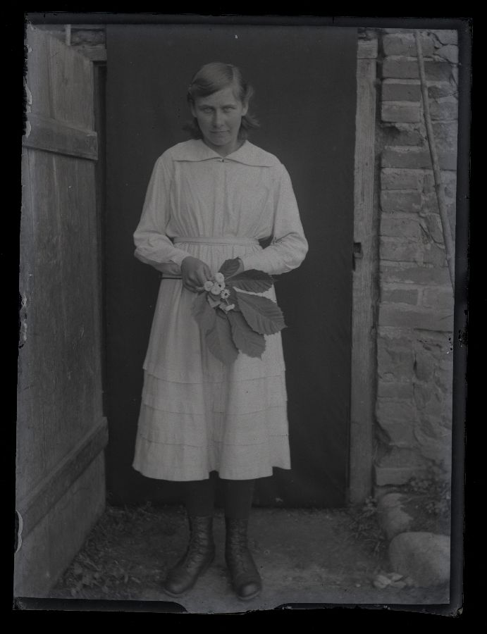 Valge kleidiga naine, pildistatud ukseavas, mille ette riputatud tekk.