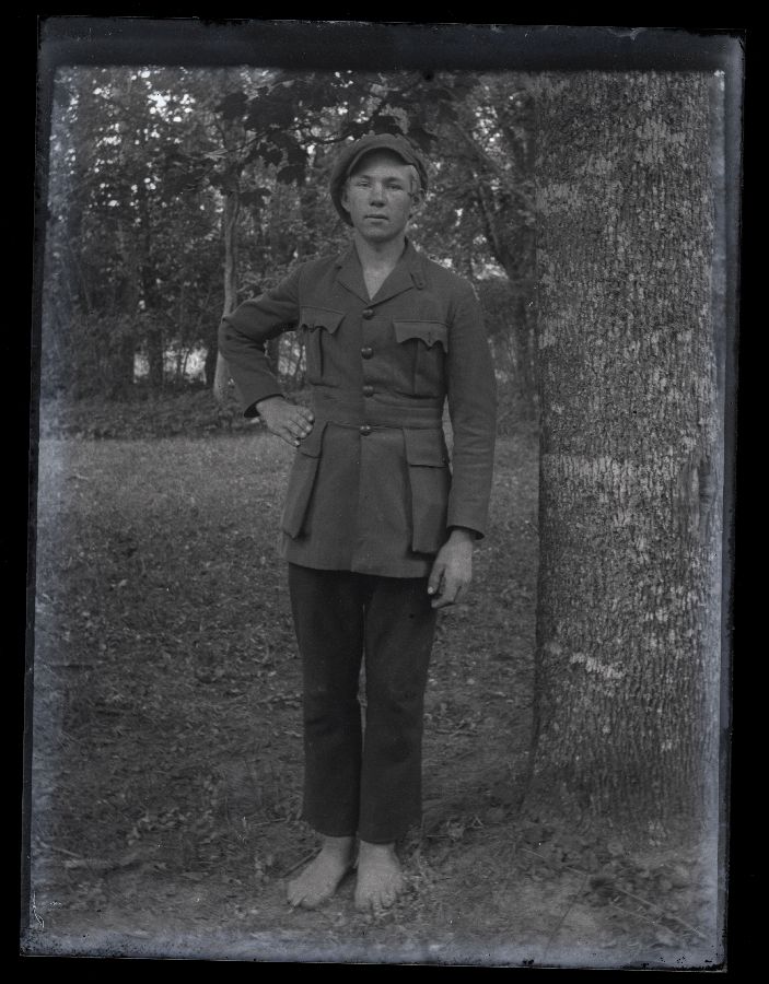 Noormehe portree, pildistatud metsas suure puu kõrval.