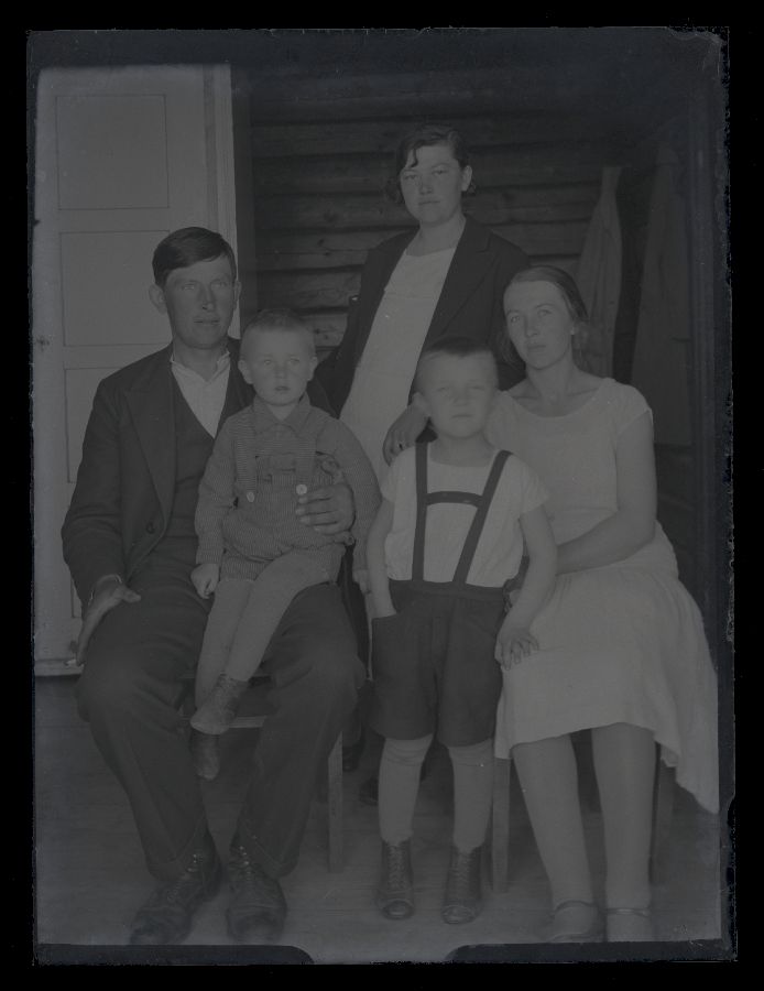 Kolm täiskasvanut ja kaks last, pildistatud toas, taustal näha toauks.
