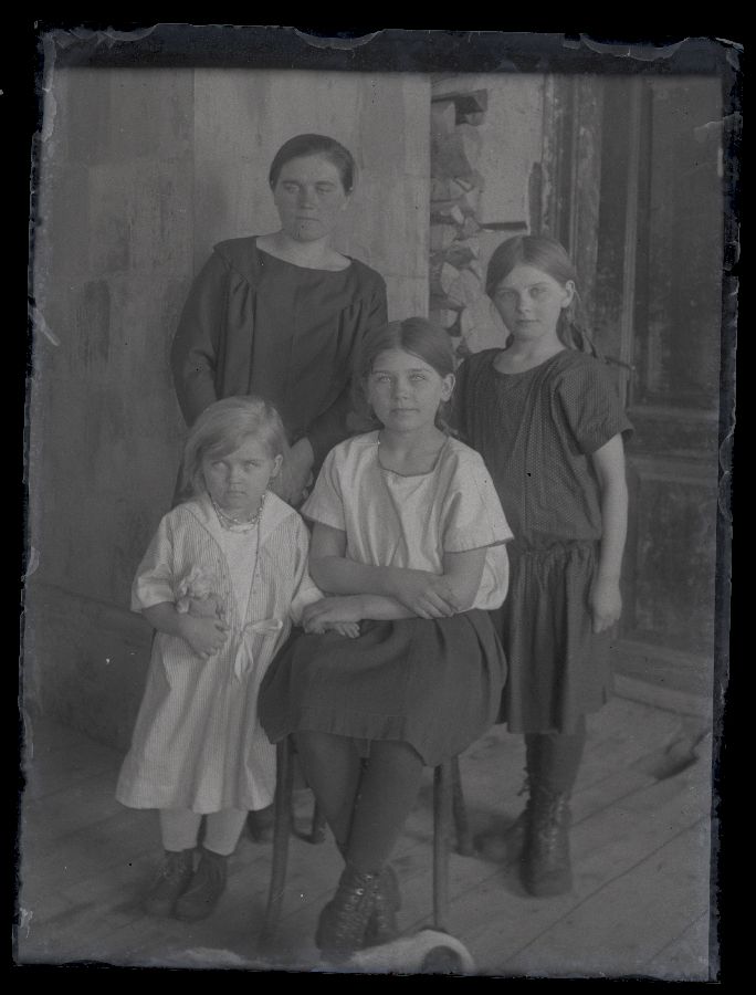 Naine koos kolme lapsega, seljataga näha toauks.