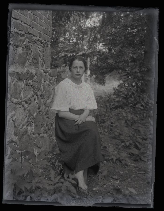 Istuva naise portree, pildistatud hoone kiviseina kõrval.