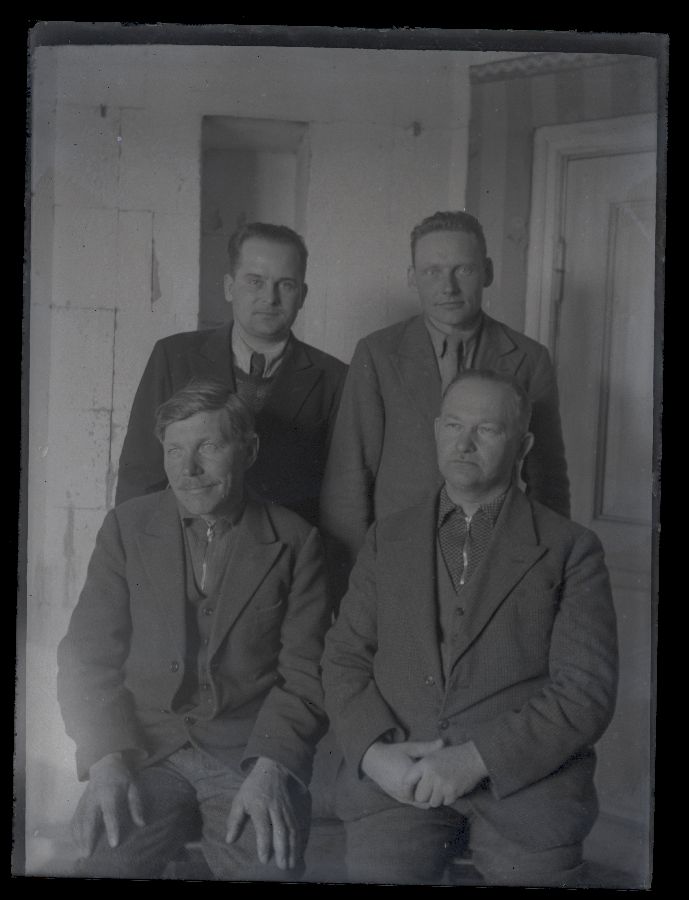 Neli meest, pildistatud toas, seljataga toauks.
