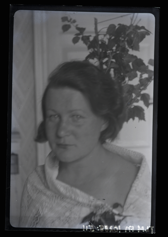 Naise portree, taustal näha mingisugune taim ja toauks.