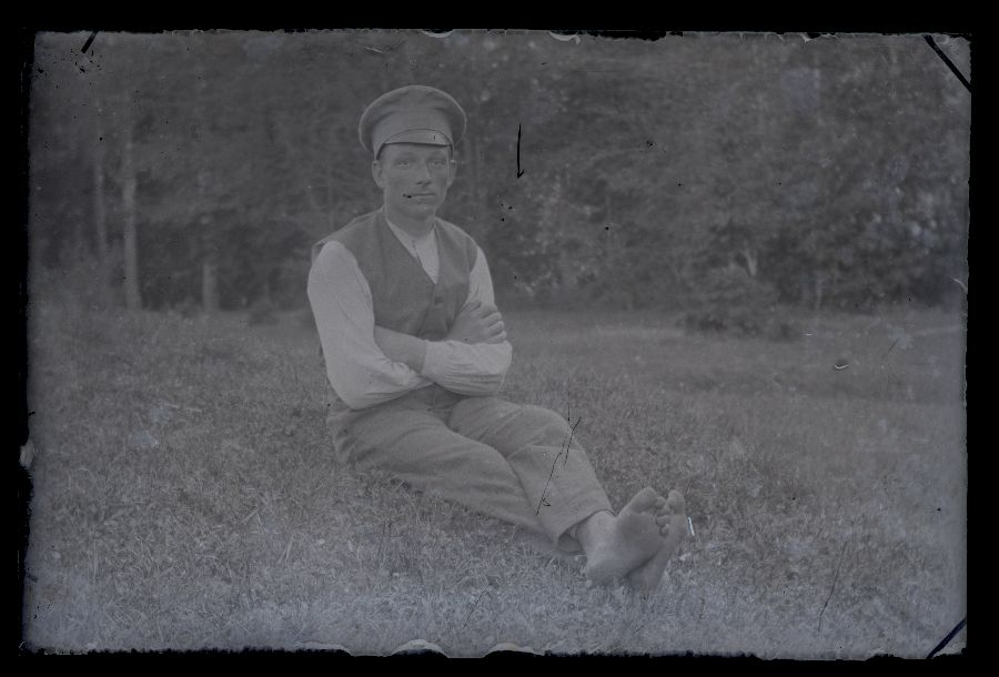 Paljasjalgne mees istub murul.