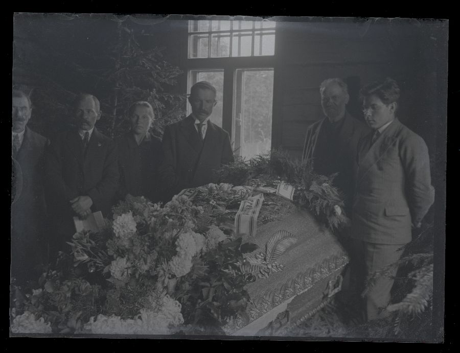 Matusefoto, suletud kirst, mille ümber seisavad matuselised.
