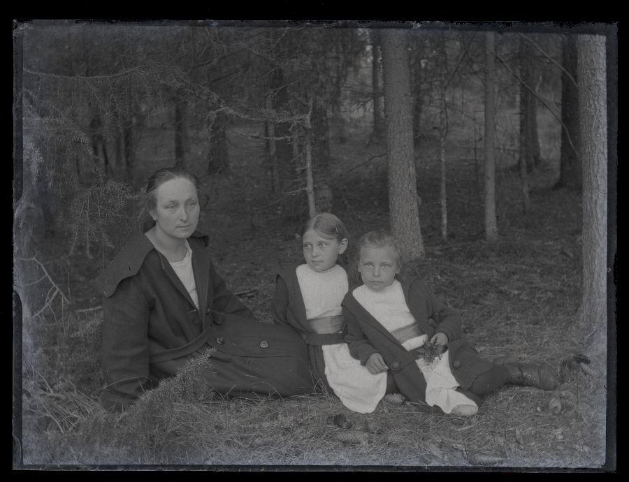 Naine kahe väikse tüdrukuga, pildistatud metsas.