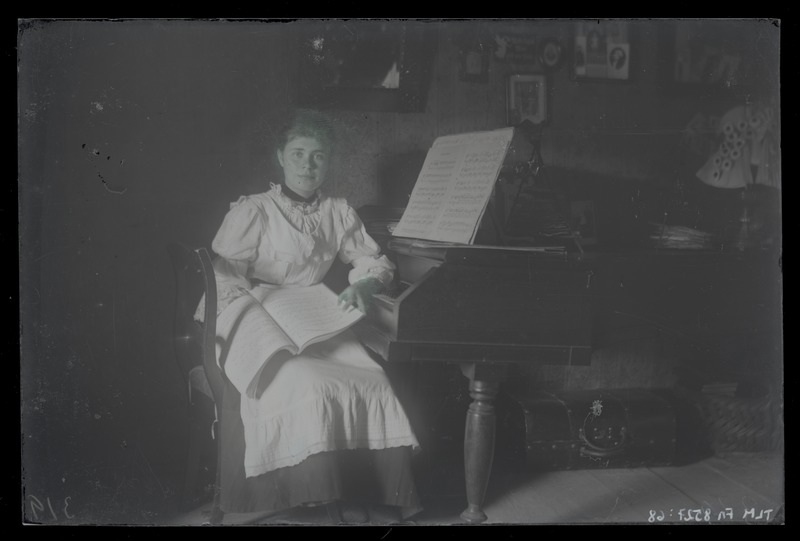 Portreefoto, neiu istumas klaveri juures, umbes 1915. aastast.