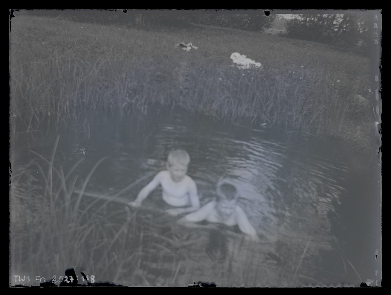 Maastikufoto, esiplaanil kaks poissi veekogus, 1920-ndad aastad.