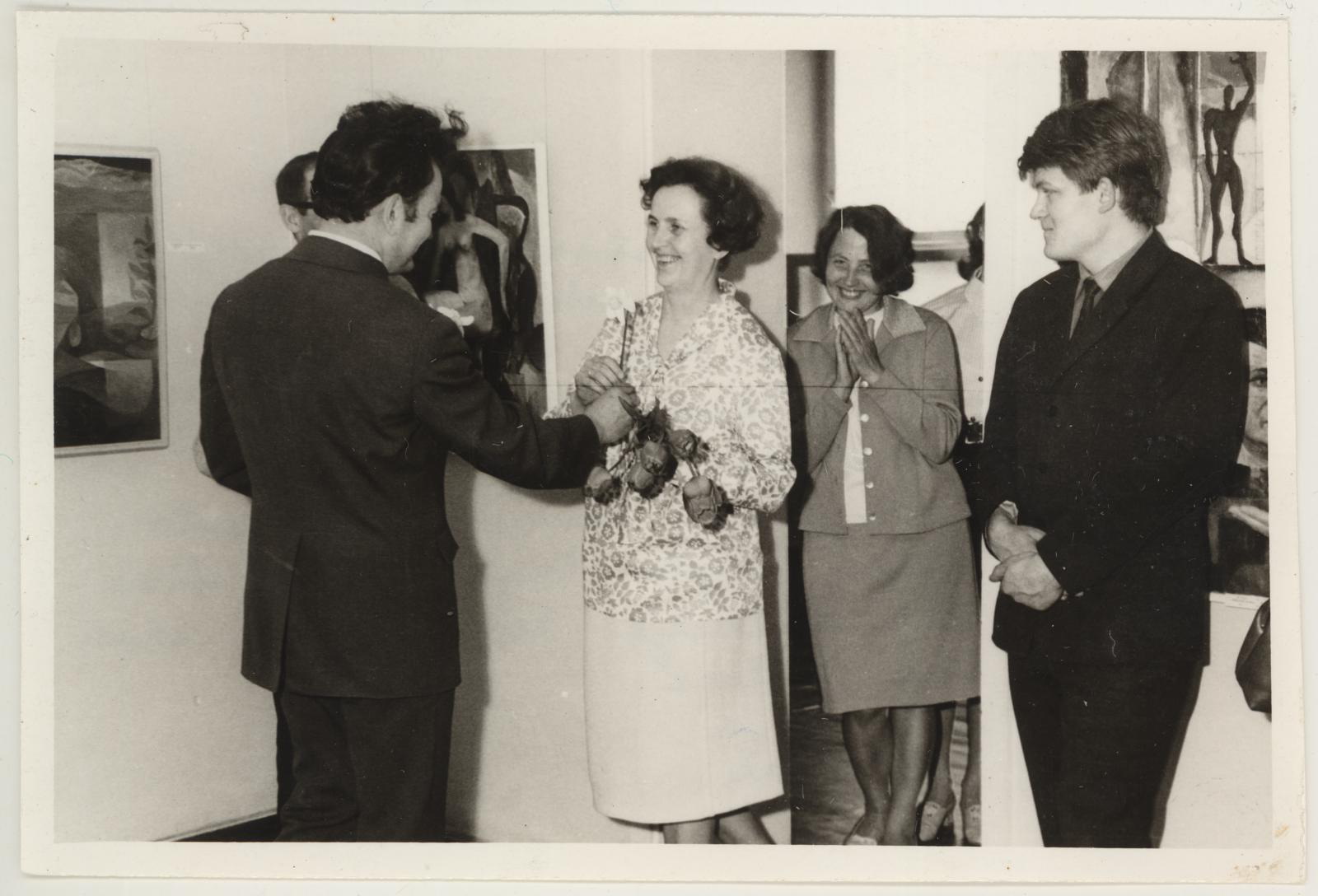 Tartu kunstinäituse avamine 14.05.1971. ENSV Kunstnike Liidu Tartu osakonna esimees annab üle nartsissiõie muuseumi direktorile Vaike Tiigile. Tema kõrval direktori asetäitja teaduslikul alal Eha Ratnik