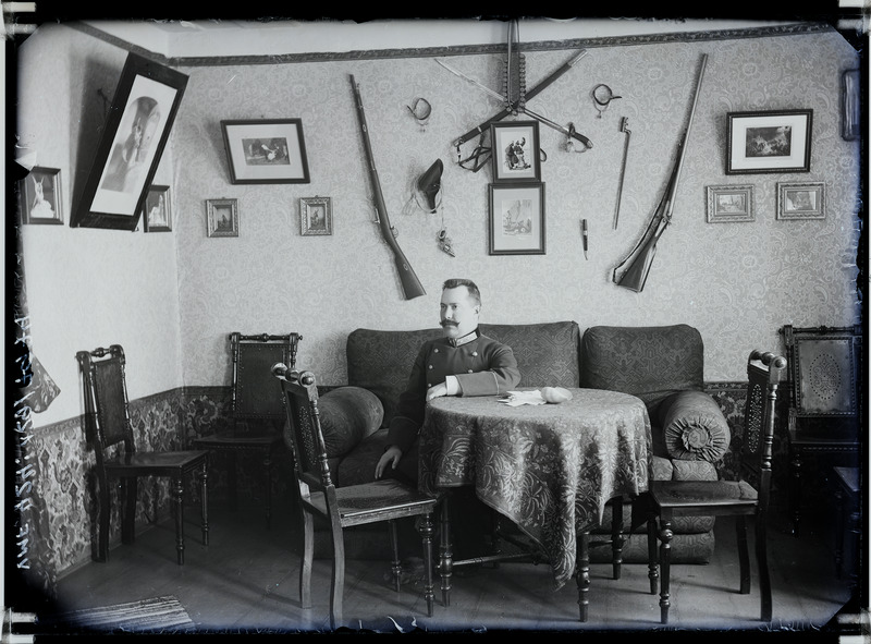 fotonegatiiv, Sokolov, meeskohtunik, elutuba, seinal relvad, 1904 foto J.Riet