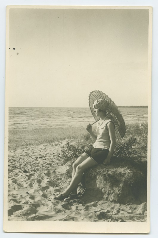 Mere ääres rannaliival  päikesevarjuga, trikoos, naine.