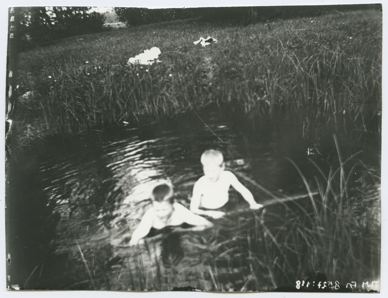 Maastikufoto, esiplaanil kaks poissi veekogus, 1920-ndad aastad.