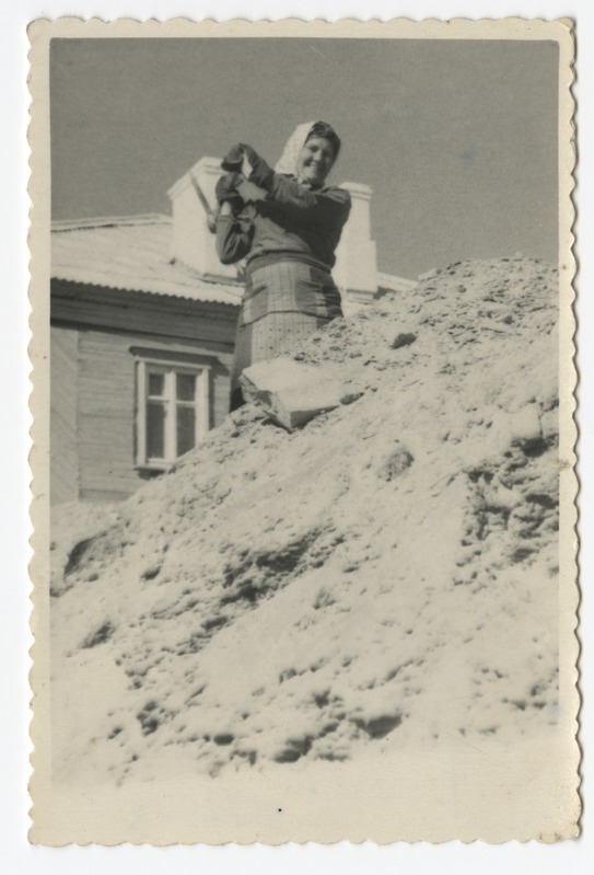 Töörõivastes naine kirkaga hoone taustal