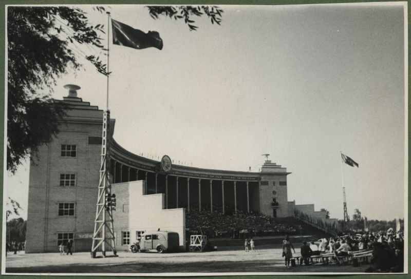 XII üldlaulupidu 28.-29. juunil 1947, Tallinnas.
12. üldlaulupidu Tallinna lauluväljakul. Külgvaates Tallinna vana laululava, mille kummalgi küljel lehvivad mastides lipud. Laululavale on koondunud esinejad. Foto paremal äärel näha laululava esiseid pinke, kus istuvad pealtvaatajad. Laululava äärde on pargitud auto.