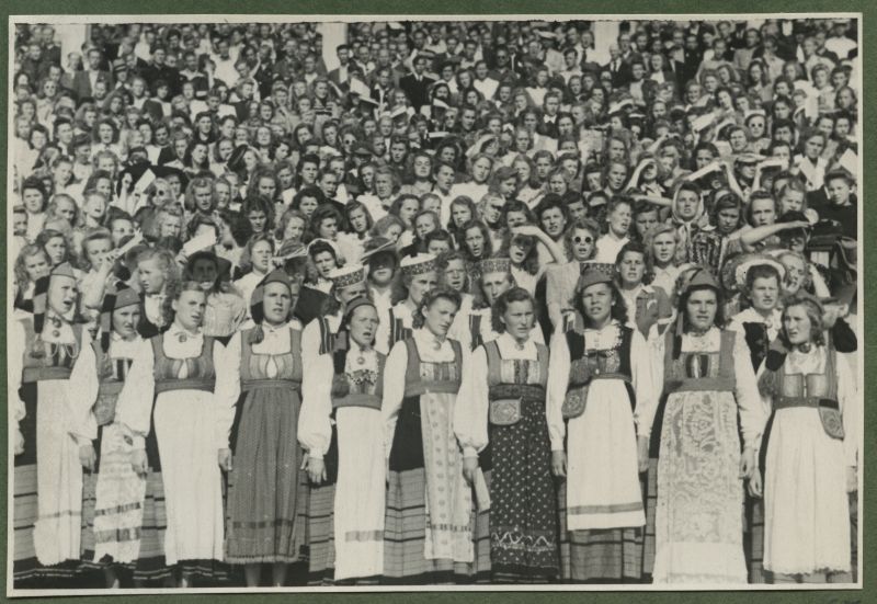 XII üldlaulupidu 28.-29. juunil 1947, Tallinnas.
Naiskooride lauljad esinemas 12. üldlaulupeol Tallinna lauluväljakul. Taga paistavad Tallinna vana laululava sambad.