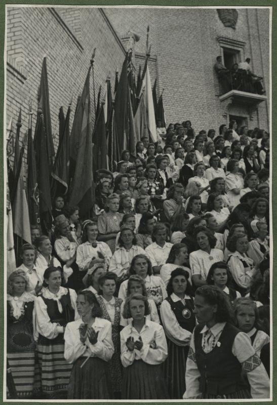XII üldlaulupidu 28.-29. juunil 1947, Tallinnas.
Naiskooride lauljad esinemas 12. üldlaulupeol Tallinna lauluväljakul. Taustal Tallinna vana laululava, mis on ääristatud erinevate lippudega. Laululava rõdul on näha pealtvaatajaid.