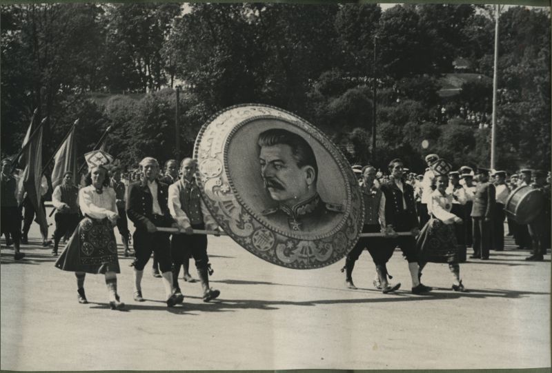 XII üldlaulupidu 28.-29. juunil 1947, Tallinnas.
12. üldlaulupeo rongkäik, 4 rahvariietesse rõivastatud meest kannavad hiiglasliku Stalini portreed, mis on raamistatud sõlge meenutava äärega. Kummalgi küljel kõnnivad rahvarõivastesse riietatud naised. 
Foto on tehtud tänasel Vabaduse Väljakul, taga paistab Harjumägi.