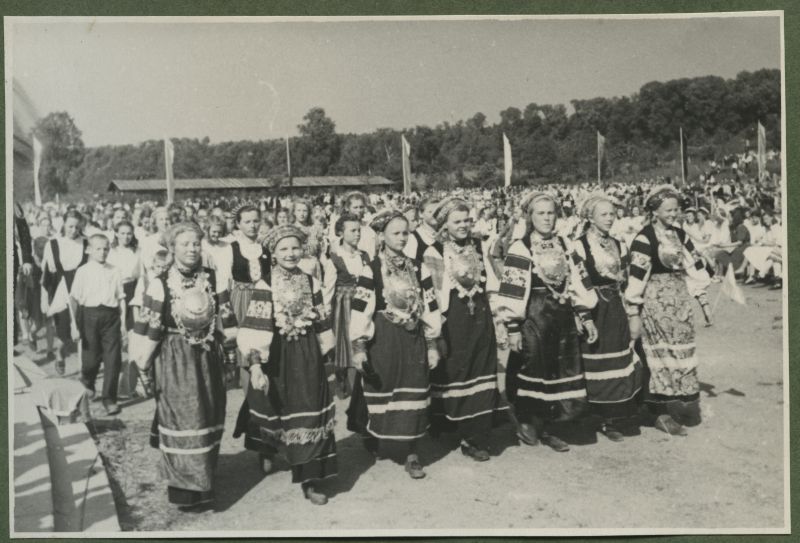 XII üldlaulupidu 28.-29. juunil 1947, Tallinnas.
12. üldlaulupeo osavõtjad rongkäigul Tallinna lauluväljakul. Eesreas Seto rahvariietes noored tüdrukud, rahvariideid ehivad suured Seto sõled. Tagaplaanil näha istuvat publikut.