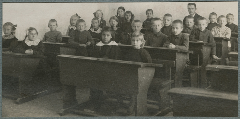 Vaade klassiruumi Juuru algkoolis (Juuru õigeusu kihelkonnakool ?), lapsed ja õpetaja Joann Ümarik istuvad pinkides.
