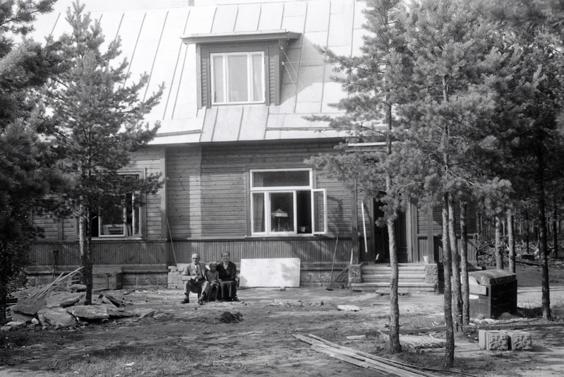 Mees ja naine poisiga maja ees istumas (Jakobson)