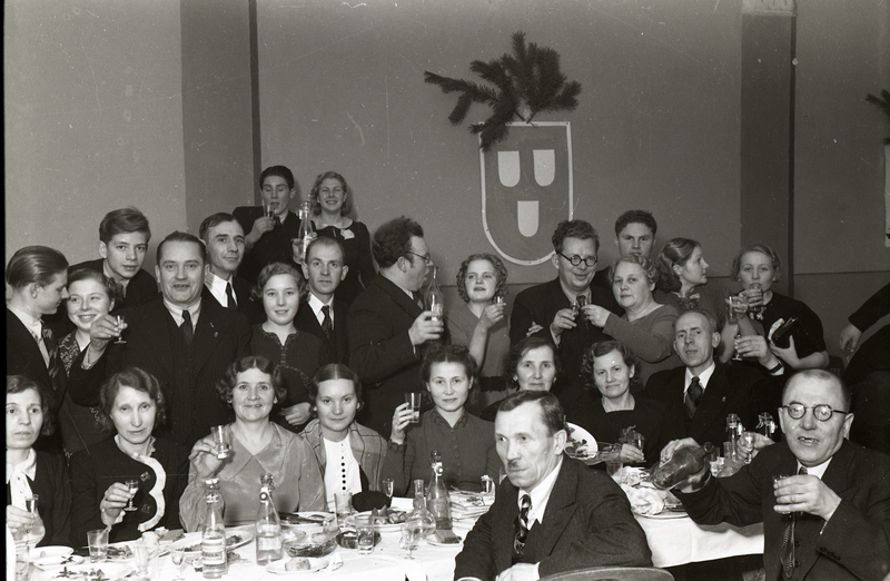 Inimesed peolaua ääres klaase tõstmas (Trükikodade Mattiesen ja Ilutrükk ühine jõulupidu 23. detsembril 1938)
