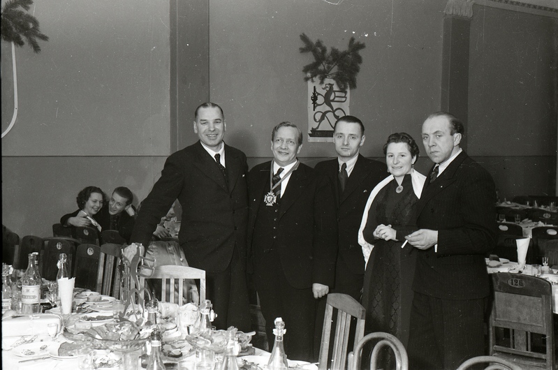 Neli meest ja naine peolaudade vahel seismas (Trükikodade Mattiesen ja Ilutrükk ühine jõulupidu 23. detsembril 1938)