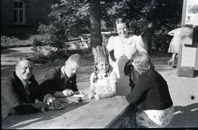 Ilutrüki trükikoja juhataja Leonhard Kahl (vasakul), mees, laps ja naine õues laua taga istumas, naine heledas kleidis nende juures seimas
