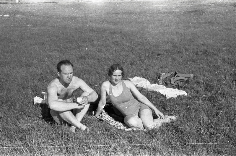Mees ja naine ujumisriietes murul istumas