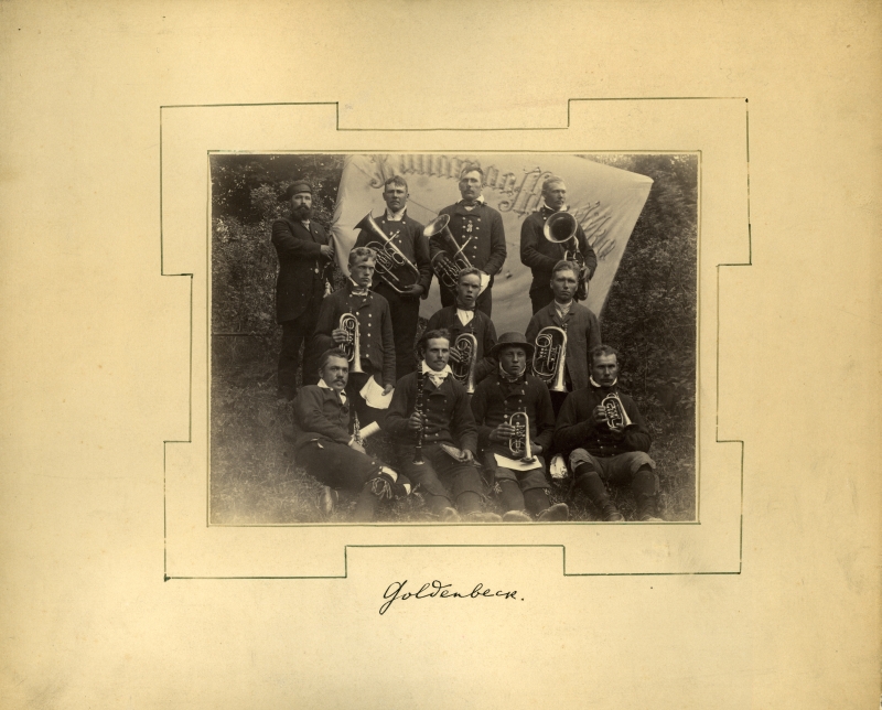 Grupipilt. Kullamaa pasunakoor Haapsalu laulupeol 1896.a. Pildil kümme rahvariides meest pasunatega, taga vasakul mees koori lipuga.