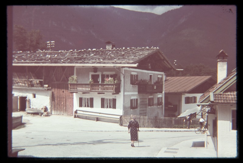 Tänavavaade, alpi-stiilis hooned, ristmikul kepiga kõndija, jalgrattur.