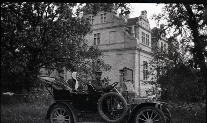 Mees, naine ja juht automobiilis. Taustal Ungru mõisa peahoone