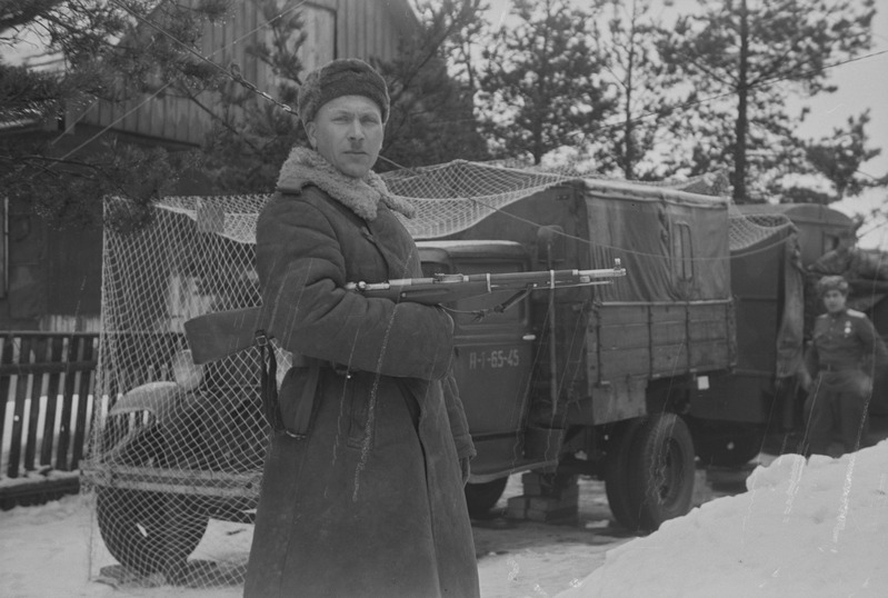 Sõdur relvaga sõjaväeauto juures poseerimas