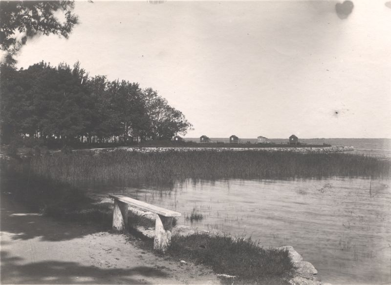 Foto. Aafrika kallas Haapsalus. Esiplaanil kaldaäärne lihtsa puust istepingiga, tagaplaanil supelmajad.  20. saj algus.