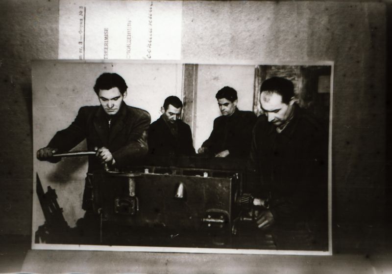 Negatiiv.  Taebla MTJ parimad traktoristid Edgar Lõps (esiplaanil vasakul) ja Aleksander Timberg (paremal) traktori mootorit remontimas.
Kopeerija: Aare Vaalma, veebruar 1980.a.