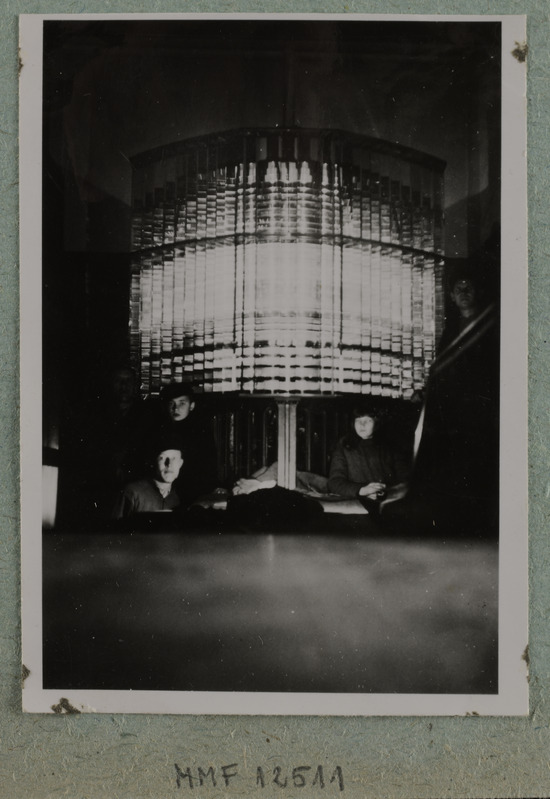 Tuletorni valgusseade ja 4 inimest selle juures