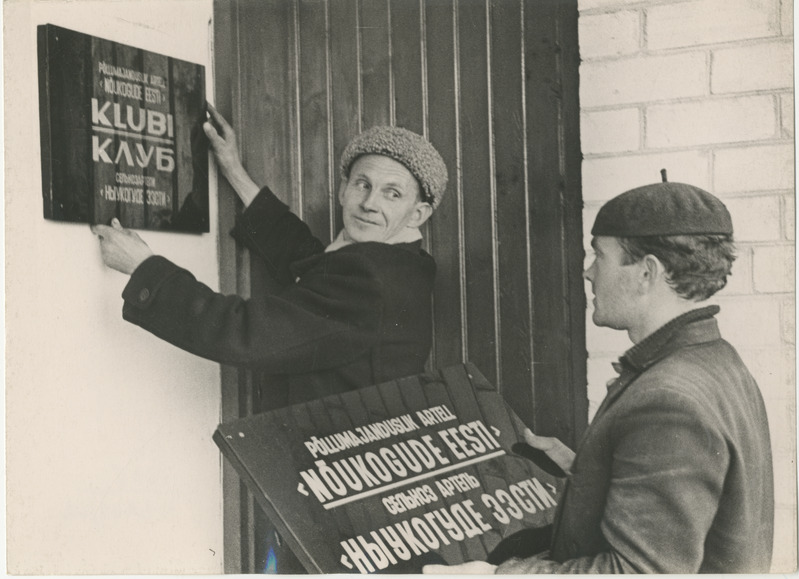 Foto. Vahenurme sovhoosi mehed paigaldavad oma klubihoonele silti.