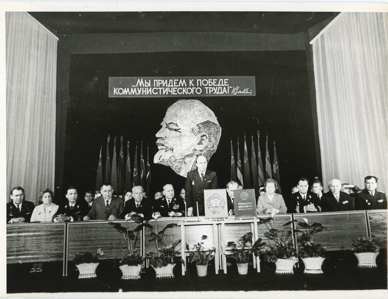 Eesti Raudteekonna kollektiivile NLKP KK, NSVL Ministrite Nõukogu, ÜAÜKN ja ÜLKNÜ KK rändpunalipu üleandmise pidulik koosolek: vaade presiidiumile, kõneleb Heino Roosma, 28.02.1975, foto: Mihkel Ollino