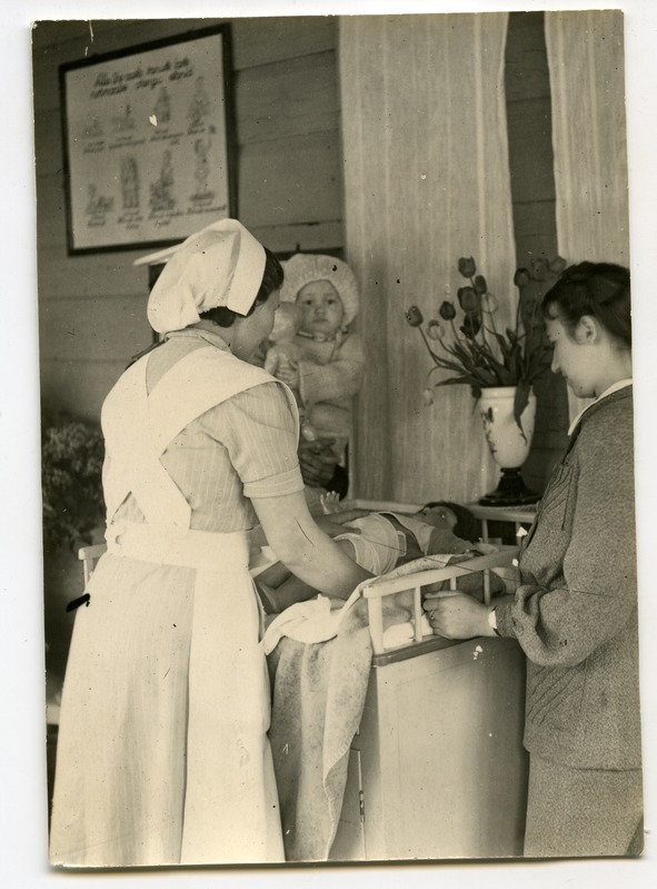 Kuressaare lastesõim: kasvataja näitab emale nuku peal imiku mähkimist