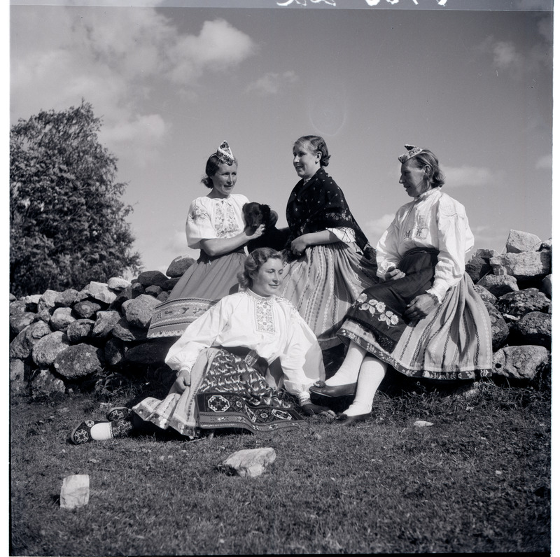 Grupp rahvariides Muhu naisi kiviaial istumas