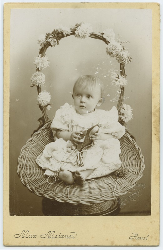 Portreepilt, aastane laps korvis istumas.